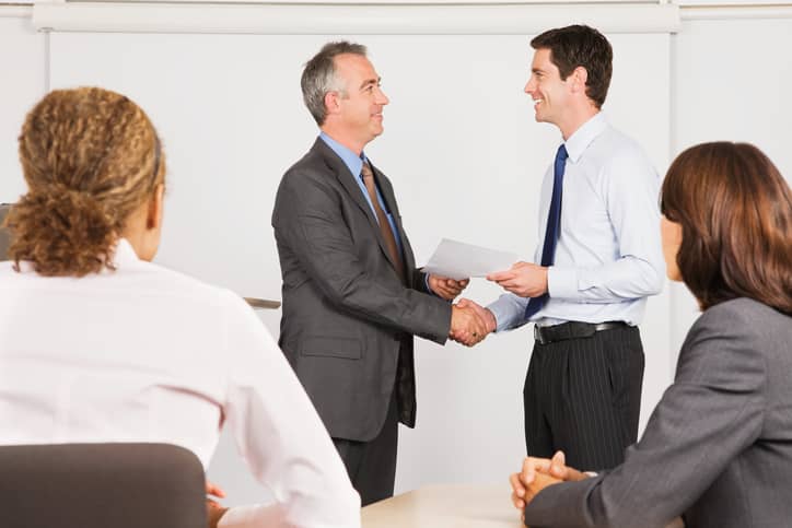 A manager handing a certification to a business professional