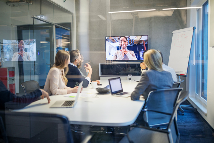 Businesswoman having video conference meeting with team sitting in board room