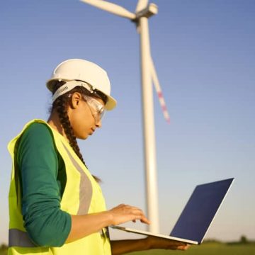 Female engineer standing in front of eco-friendly wind turbines