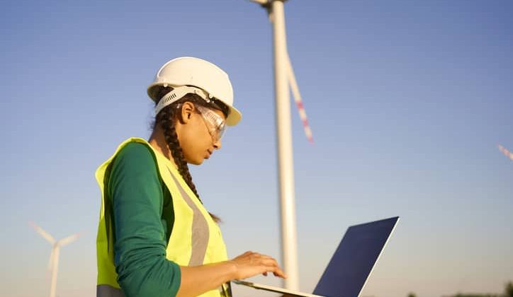 Female engineer standing in front of eco-friendly wind turbines