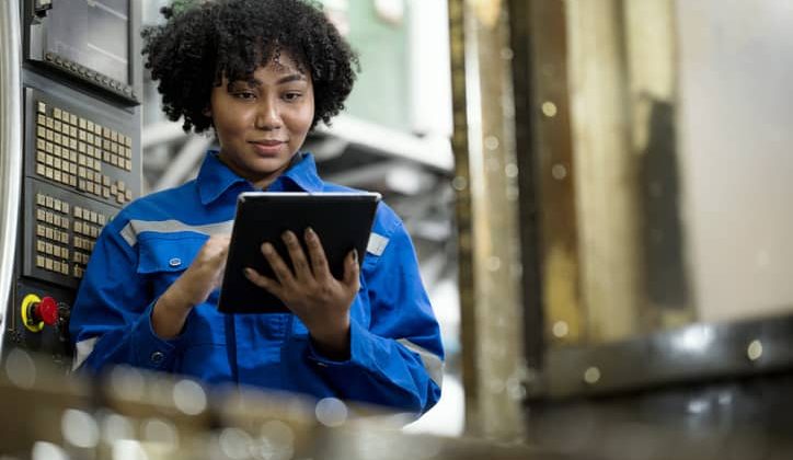 African American female engineer using a tablet to check for defects on the production line