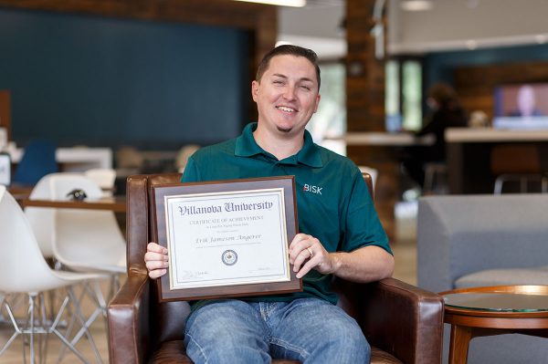 Bisk employee smiles as he poses with his certificate from tuition assistance programs