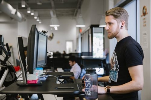 Bisk employee looks at his monitors while at his standing desk