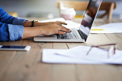 Cropped shot of a woman using a laptop while working from home