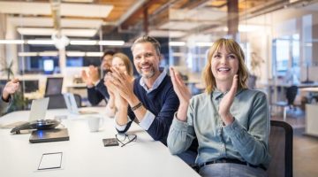 Multi-ethnic business group applauds in an office meeting