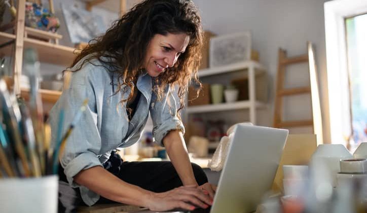 Female small business owner types on computer in working office