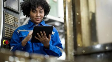 African American female engineer using a tablet to check for defects on the production line
